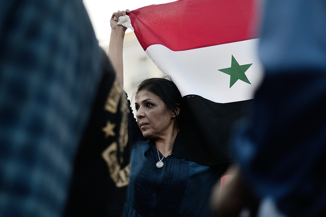 Una mujer porta la bandera de Siria